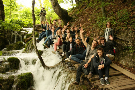 Gruppenfoto im Wald. Daneben sind kleine Wasserfälle.