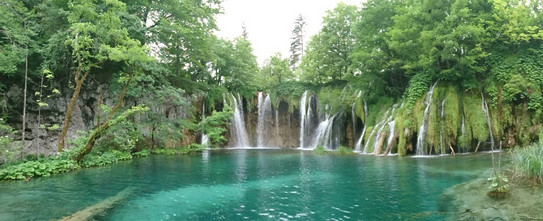 See und kleine Wasserfälle in einem Wald.