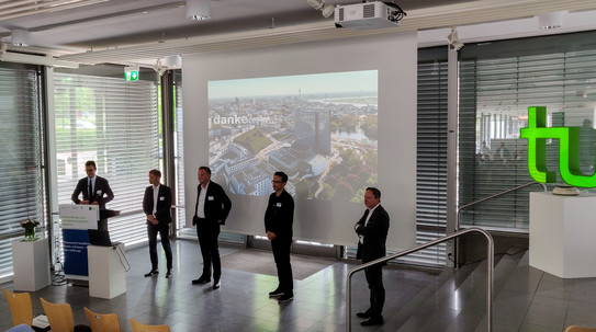 5 Vortragende stehen vor der Leinwand.