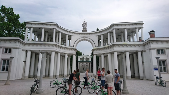 Fahrradfahrer vor weißen Gebäude mit Säulen.